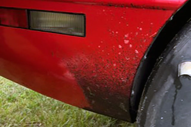 Dirty rear quarter panel on red corvette.