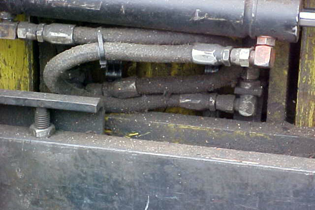Heavy grease build-up on forklift hydraulic hoses and frame.