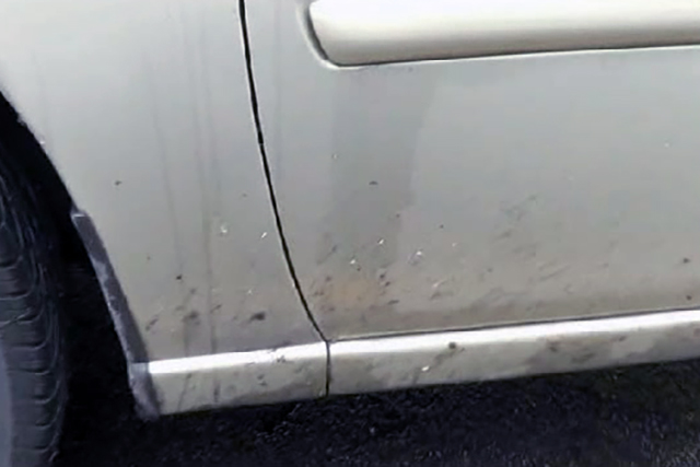 Road dirt and tar on side of vehicle.